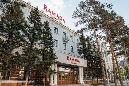 阿斯塔纳Ramada by Wyndham Astana的白色的建筑,上面有红色的标志