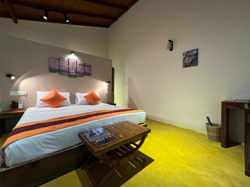 维勒珀图Cloud Nine Wilpattu by Aaradhya的一间卧室配有带橙色枕头和桌子的床
