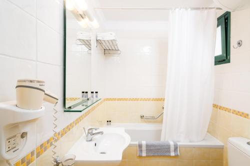 古维亚Helion Resort的浴室配有水槽、浴缸和淋浴帘