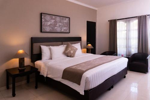 塞米亚克Sarinande Hotel的一间卧室配有一张大床和一把椅子