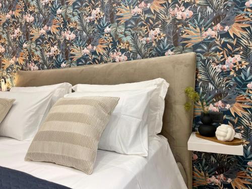 佩斯卡拉Regina Elena Rooms的一张带白色枕头和花卉壁纸的床