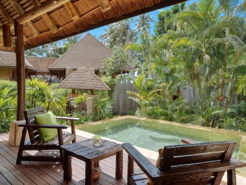 库德岛旺季泳池别墅& Spa的庭院设有游泳池、两把椅子和一张桌子
