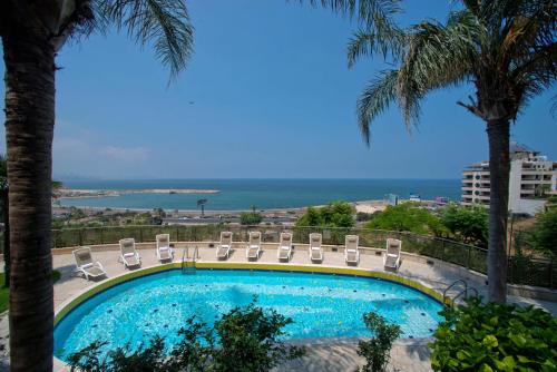 贝鲁特贝鲁特皇家度假村的一个带椅子的游泳池,背景是大海