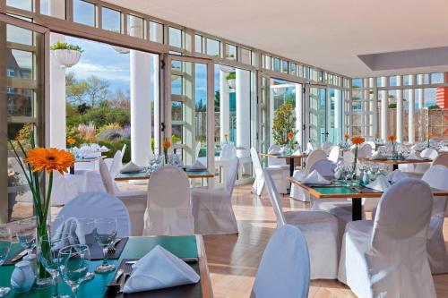 马德普拉塔马德普拉塔喜来登酒店 的用餐室设有桌子和白色的椅子以及窗户。