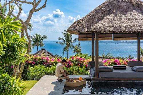 金巴兰AYANA Villas Bali的坐在度假村游泳池旁的人