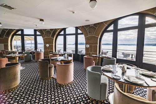 迪纳尔Castelbrac Hotel & Spa的餐厅设有桌椅和窗户。
