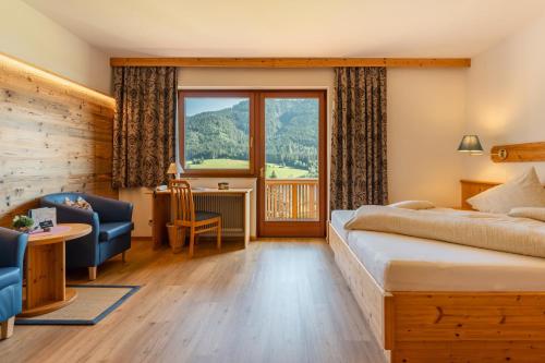 魏森湖Wiesenhof, Hotel direkt am See的酒店客房设有一张床和一个大窗户