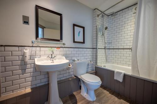 亚特Cross Hands Hotel by Greene King Inns的浴室配有卫生间、盥洗盆和浴缸。