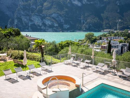 加尔达湖滨Hotel Benacus Panoramic的一个带游泳池、椅子和水体的庭院