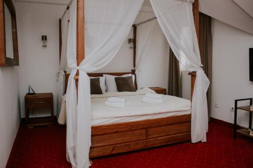 莫伊科瓦茨Hotel Serdar的卧室配有带白色窗帘的天蓬床