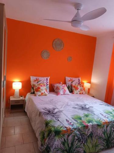 波尔兰特Bas de villa (T4) proche de la plage的一间卧室设有橙色墙壁和一张带枕头的床