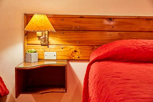 Rodeo de la CruzHostal de Los Andes的一间卧室配有一张床和一张带台灯的桌子