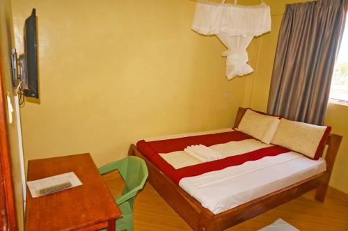 BusiaMipeja Hotel的一间小卧室,配有一张床和一张桌子