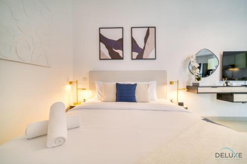 迪拜Placid Studio at Afnan 4 Midtown Dubai Production City by Deluxe Holiday Homes的白色卧室配有一张大白色的床和两面镜子