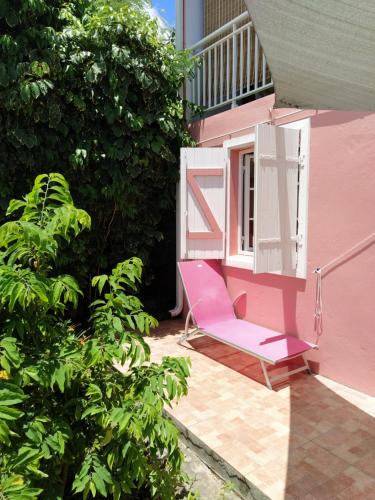 大博格Dous'Inn Kreyol Appartement的粉红色椅子坐在粉红色房子的门廊上