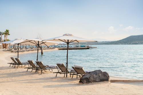 阿拉恰特Biblos Resort Alaçatı的海滩上的一组椅子和遮阳伞