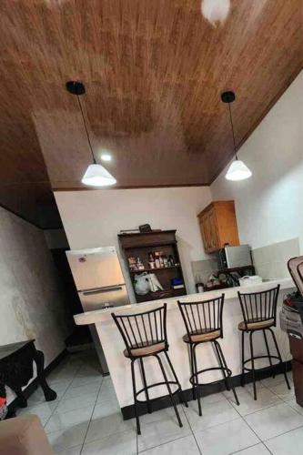 马塔加尔帕Casa Sunshine的厨房配有三把吧台凳和台面