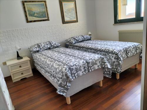 龙基德伊莱焦纳里Finestre Verdi appartamento con parcheggio的一间卧室配有两张床,还有一个床头柜和一张桌子
