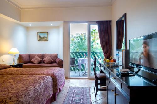 马拉喀什Kennedy Hospitality Resort的配有一张床和一台平面电视的酒店客房