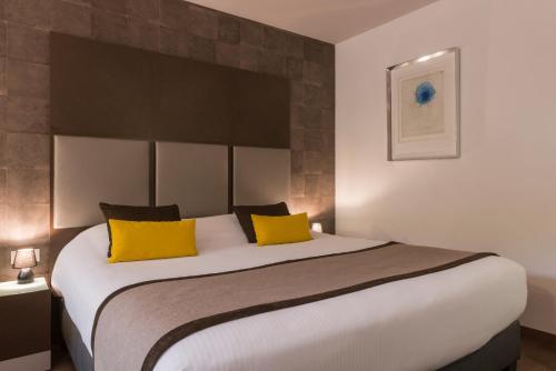 莫尔塞姆Hôtel Diana Restaurant & Spa by HappyCulture的一间卧室配有一张带黄色枕头的大床