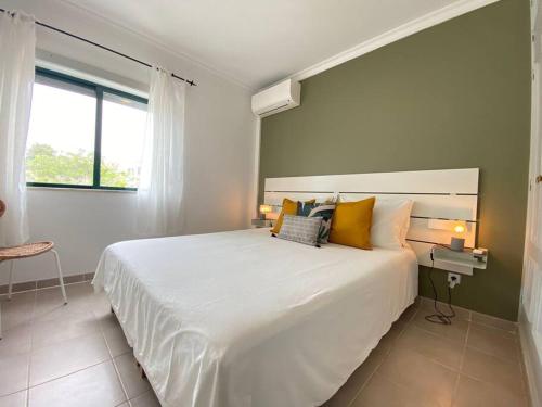 卡武埃鲁Apartamento Amparo-T2 c/piscina的卧室配有一张带黄色枕头的大型白色床。