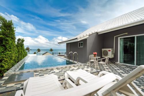 Ban Ao Makhammona seaview pool villa beach front AoYon Beach的一个带白色椅子的庭院和一个游泳池