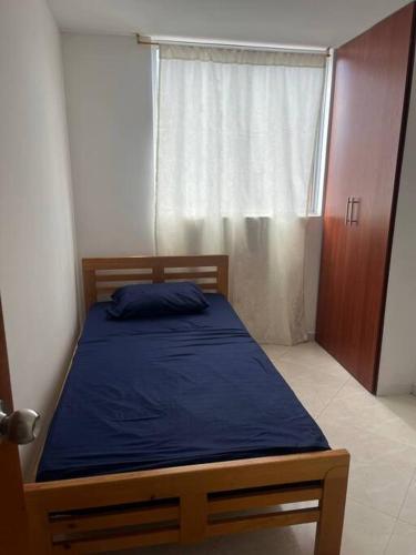 布卡拉曼加Apartamento bien ubicado.的一间卧室配有一张带蓝色毯子的床和窗户。
