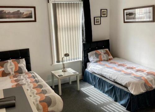布莱克浦The Hotel Blackpool的一间卧室设有两张床、一张桌子和一个窗口