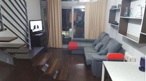 马德里Ático,loft ,duplex的客厅配有灰色的沙发和红色的椅子