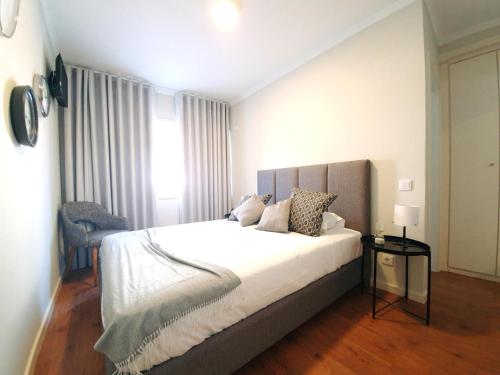 波尔图Sonetos - Guest House的卧室配有一张白色大床和一把椅子