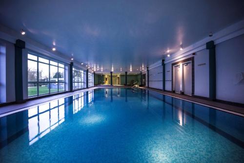 切尔滕纳姆切尔滕纳姆希尔顿逸林酒店的大楼内的一个蓝色海水游泳池