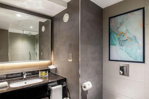 希灵登Hilton Garden Inn London Heathrow Terminal 2 and 3的一间带水槽和大镜子的浴室