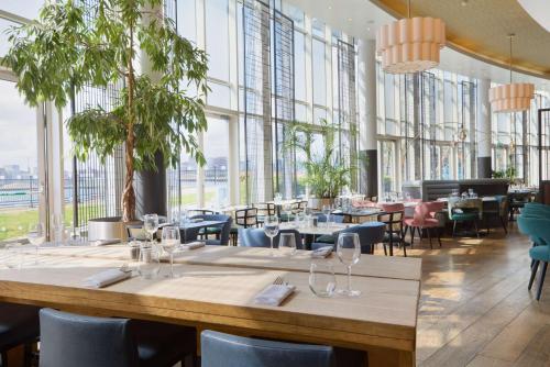 伦敦伦敦超越希尔顿逸林酒店的餐厅设有桌椅和大窗户。