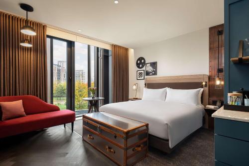 伦敦The Gantry London, Curio Collection By Hilton的酒店客房,配有一张床和一张红色椅子