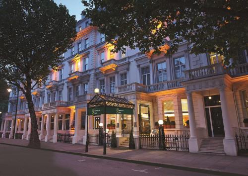 伦敦100 Queen’s Gate Hotel London, Curio Collection by Hilton的前面有商店的白色建筑