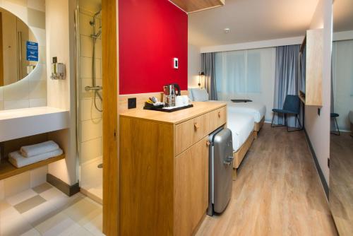 伦敦Hampton by Hilton London Park Royal的酒店客房,设有床铺和红色的墙壁