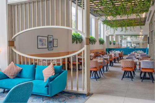 特伦特河畔斯托克Hilton Garden Inn Stoke On Trent的餐厅设有蓝色的沙发和桌椅