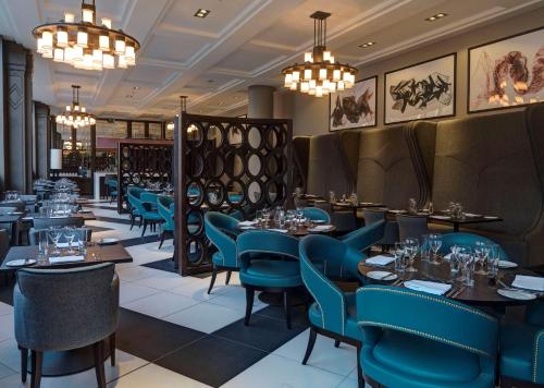爱丁堡爱丁堡市中心希尔顿逸林酒店的餐厅设有蓝色的桌椅和吊灯。