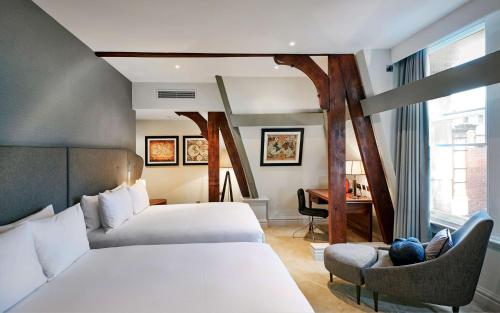 利物浦利物浦希尔顿逸林酒店的酒店客房配有两张床、一把椅子和一张书桌