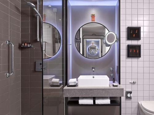 伦敦特拉法加圣詹姆斯，伦敦希尔顿Curio Collection酒店的浴室配有盥洗盆和带镜子的淋浴