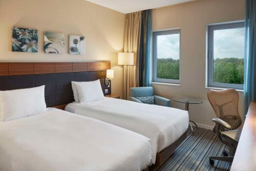 美因河畔法兰克福希尔顿花园法兰克福空港酒店的酒店客房带两张床、一张桌子和两个窗户。