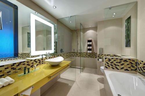 美因河畔法兰克福希尔顿法兰克福机场酒店的一间带水槽、浴缸和镜子的浴室