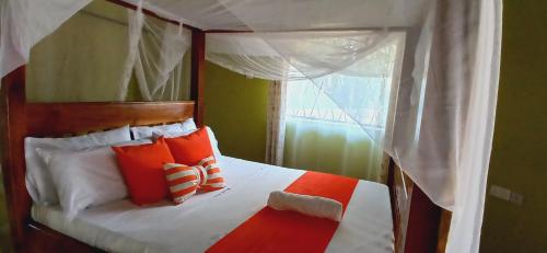 姆特瓦帕Omnia Resort的一间卧室配有带橙色和白色枕头的天蓬床