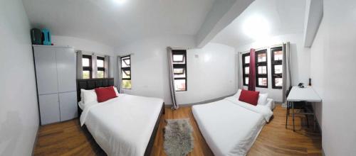 巴斯科Lorenzo's Homestay的配有2张床的白色墙壁和窗户客房