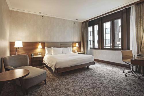 米兰希尔顿米兰酒店的酒店客房,配有一张床、一张桌子和椅子