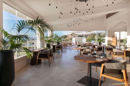 罗通多港Sulià House Porto Rotondo, Curio Collection by Hilton的餐厅设有桌椅和大窗户。