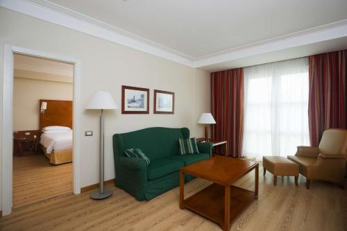 菲乌米奇诺希尔顿罗马机场酒店的客厅配有绿色沙发和床。