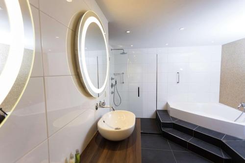 索斯图尼恩DoubleTree by Hilton Royal Parc Soestduinen的白色的浴室设有水槽和镜子