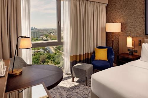 维也纳Hilton Vienna Park的配有一张床、一张书桌和一扇窗户的酒店客房