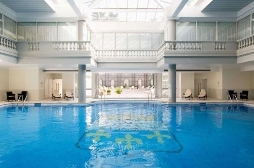 凡尔赛Waldorf Astoria Versailles - Trianon Palace的一座带大型天花板的建筑中的游泳池